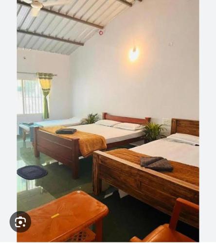 a room with three beds and a table and a chair at Lake Flower Homestay in Chikmagalūr