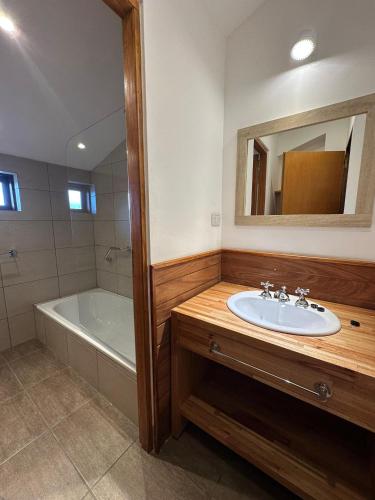 a bathroom with a sink and a tub and a mirror at Haven Patagonia in El Calafate
