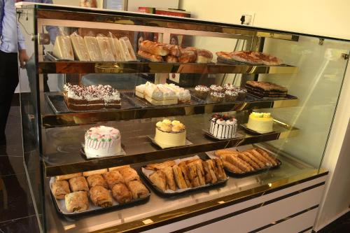 een vitrine gevuld met verschillende soorten gebak en gebak bij Hotel Shreya Galaxy with Swimming Pool- Best Property in Haridwar in Haridwār