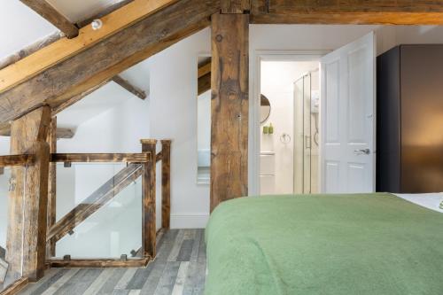 a bedroom with a green bed and wooden beams at Bradford Luxury Central Apartment in Bradford