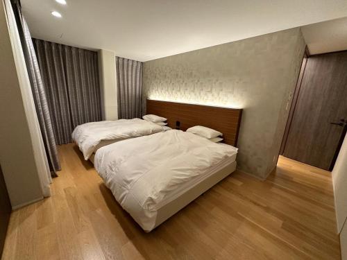 two beds in a hotel room with white sheets at SuiShou in Kutchan