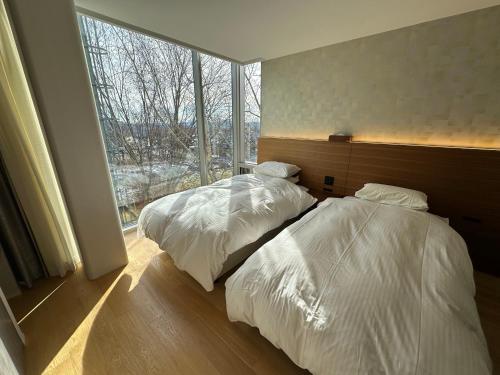 two beds in a bedroom with a large window at SuiShou in Kutchan