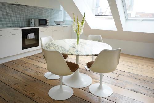 a white dining room with a glass table and chairs at B&B Home & the City in Brussels