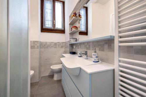 a white bathroom with a sink and a toilet at Casa vacanze da rosa in Iseo