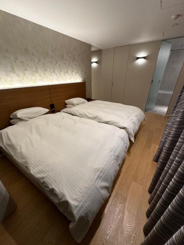a bedroom with two beds with white sheets at SuiShou in Kutchan