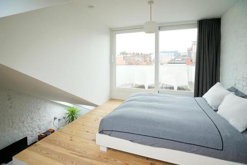 a bedroom with a bed and a large window at B&B Home & the City in Brussels