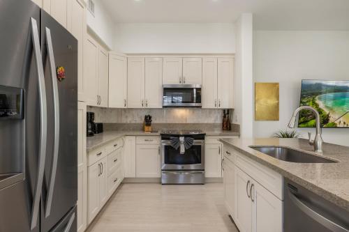 a kitchen with white cabinets and a stainless steel refrigerator at Coconut Plantation 1078-3 in Kapolei