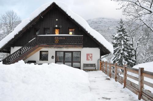 une maison recouverte de neige devant une clôture dans l'établissement La Grange Aux Loups, à Queige