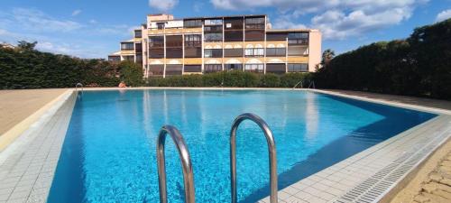 une piscine avec un bâtiment en arrière-plan dans l'établissement Naturistecapdagde APHRODITE, au Cap d'Agde