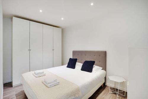 une chambre blanche avec un grand lit avec des oreillers bleus dans l'établissement Magnificent apartment - 2BR-6P - Levallois-Perret, à Levallois-Perret