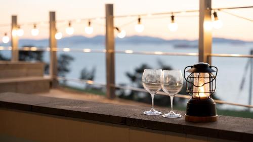 two wine glasses and a lantern sitting on a ledge at Namhae Mansion Morak in Namhae