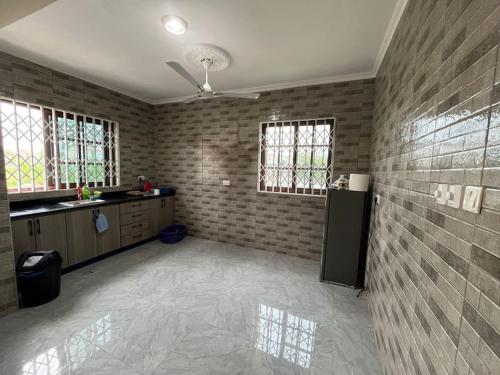 a large room with a kitchen with a ceiling fan at Alpha Rooms Single Bedroom Gome Fortress Business Center Dansoman Accra in Accra