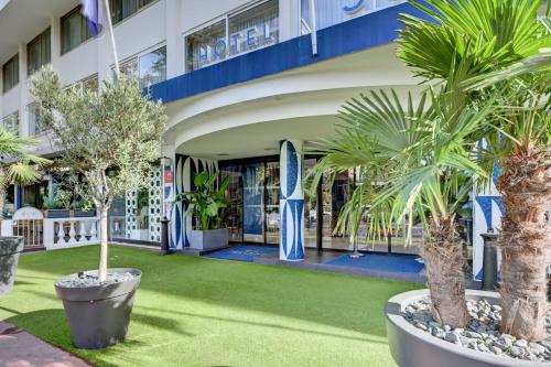 a hotel with palm trees in front of a building at Juliana Hotel Cannes in Cannes