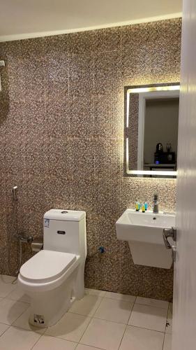 a bathroom with a toilet and a sink and a mirror at Golden New Tulip Abha in Abha