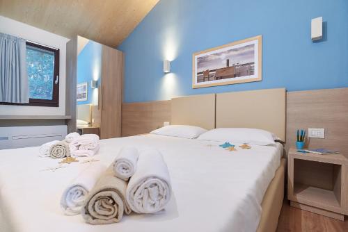 a bedroom with a large white bed with towels on it at Paradù EcoVillage & Resort in Marina di Castagneto Carducci