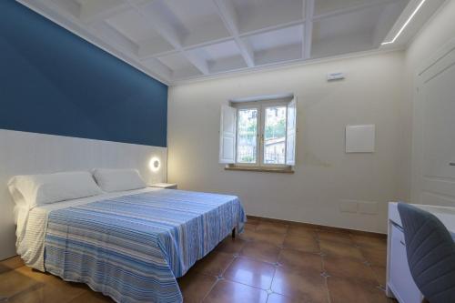 a blue and white bedroom with a bed and a window at Morrone Inn in Marano Marchesato