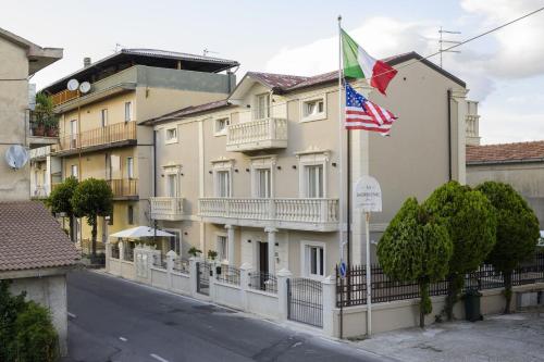 a building with an american flag and a building with a fence at Morrone Inn in Marano Marchesato
