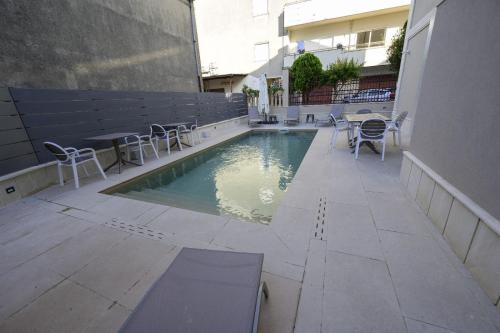 a swimming pool with chairs and a table and a building at Morrone Inn in Marano Marchesato