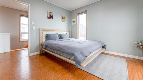 a bedroom with a large bed in a room with wood floors at Jeju Jongdal Private Pension in Jeju
