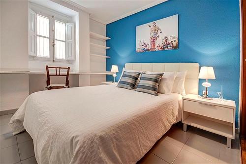 een blauwe slaapkamer met een bed en een stoel bij Beds & Breaks Danna in Valencia