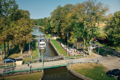 ein Boot, das über einen Fluss mit einer Brücke fährt in der Unterkunft Hajstorp Slusscafé & Vandrarhem in Töreboda