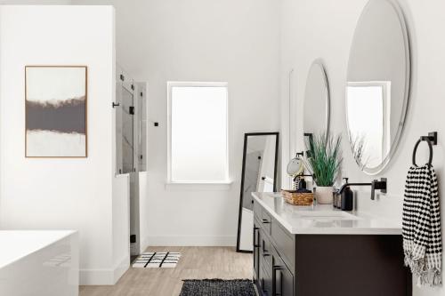 a white bathroom with a sink and two mirrors at Designer Home with Hot Tub BBQ & Hill Views in Driftwood
