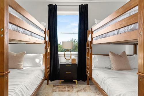 two bunk beds in a room with a window at Designer Home with Hot Tub BBQ & Hill Views in Driftwood