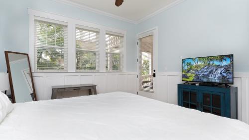 a white bedroom with a bed and a flat screen tv at Coconut Plantation 1110-3 in Kapolei