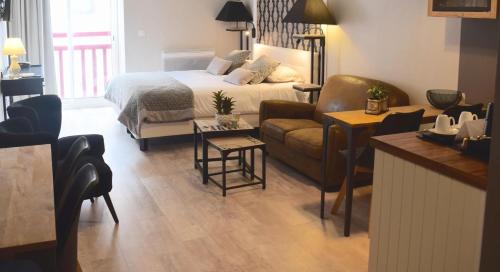 a bedroom with a bed and a living room with a couch at Le Trophée Boutique Hôtel Spa- La Loggia Appart'hôtel in Deauville