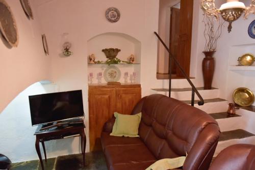 a living room with a leather couch and a television at Casa dos Avós in Évora Monte