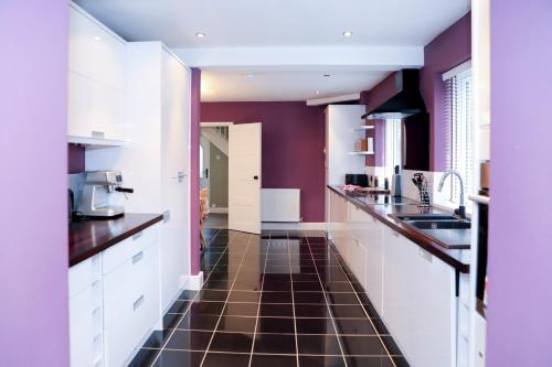 cocina con armarios blancos y suelo de baldosa marrón en Hassocks Hideaway with Parking Garden, en Hassocks