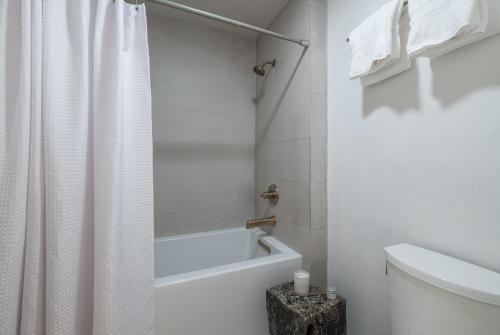 a white bathroom with a shower curtain and a toilet at Wildflower 650 in Sun Valley