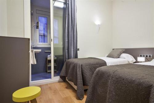 a bedroom with two beds and a sliding glass door at Alcam Trafalgar in Barcelona