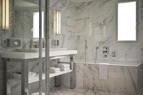 a white bathroom with a sink and a tub at Juliana Hotel Cannes in Cannes