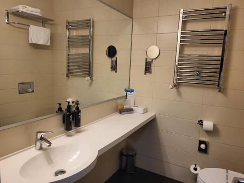 a bathroom with a sink and a mirror and a toilet at Wyndham Cluj in Cluj-Napoca