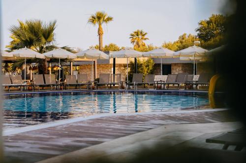 a swimming pool with tables and chairs and umbrellas at Prive Hotel Didim - Ultra All Inclusive in Didim