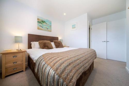 a bedroom with a large bed and a dresser with a lamp at Modern Apartment nr Fistral Beach Private Parking in Newquay