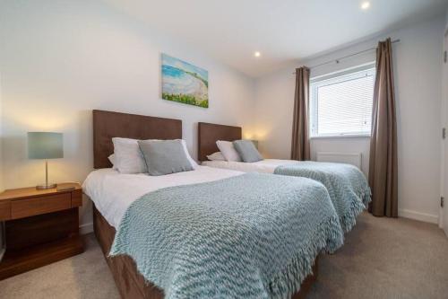 a bedroom with two beds and a table and a window at Modern Apartment nr Fistral Beach Private Parking in Newquay