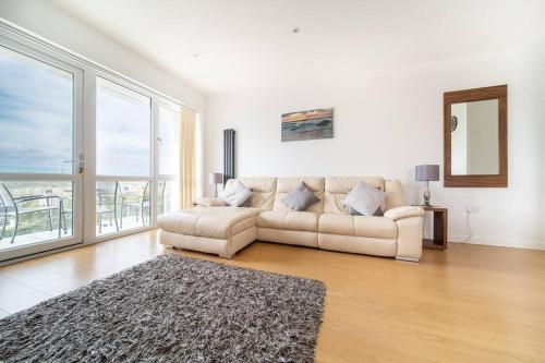 a living room with a couch and a large window at Modern Apartment nr Fistral Beach Private Parking in Newquay