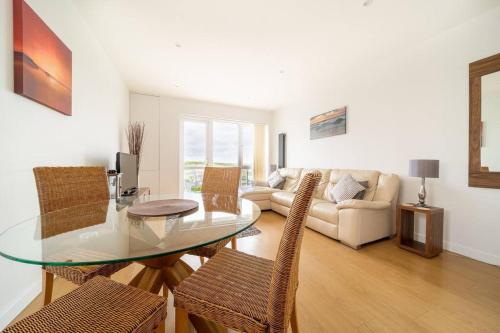 a living room with a glass table and chairs at Modern Apartment nr Fistral Beach Private Parking in Newquay