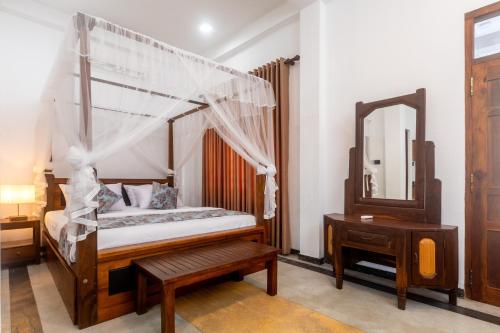 a bedroom with a canopy bed and a mirror at Villa Serenita Weligama in Weligama