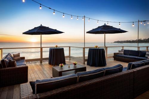 a patio with couches and umbrellas and the ocean at Pacific Edge Hotel in Laguna Beach