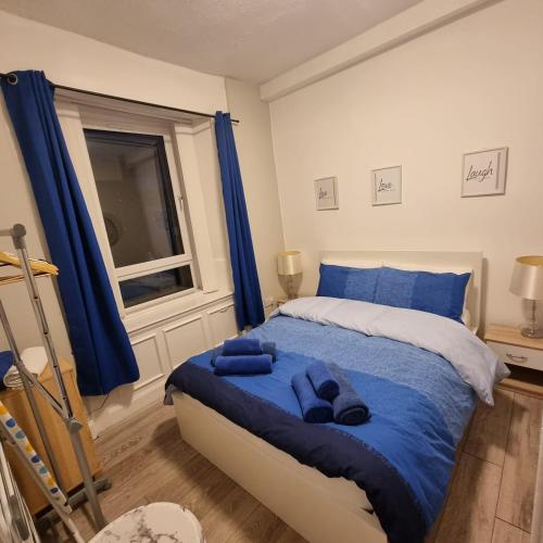a bedroom with a bed with blue sheets and a window at Carrick - One Bed Apartment in Largs