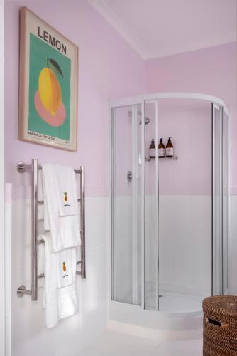 a white bathroom with a shower and towels at Petit Pineapple House in Cape Town