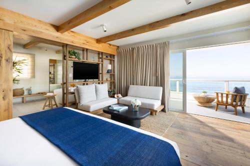 a bedroom with a blue bed and a living room at Pacific Edge Hotel in Laguna Beach