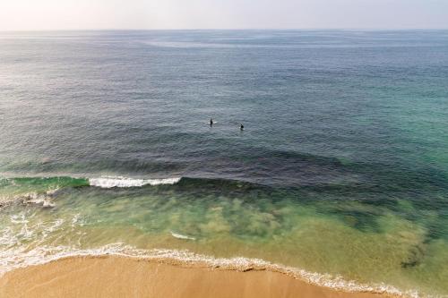 two people are in the water at the beach at Pacific Edge Hotel in Laguna Beach