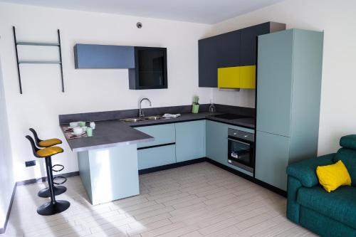 a small kitchen with blue cabinets and a green couch at UpCerro Rent - Appartamento vicino Rho Fiera - Malpensa in Cerro Maggiore