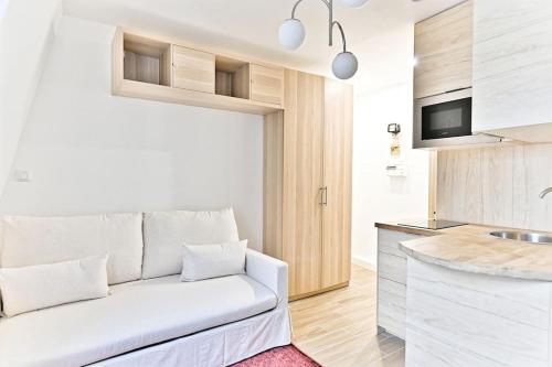 un salon avec un canapé blanc et une cuisine dans l'établissement Studio à 10 minutes de la Basilique du Sacré-Cœur, à Paris