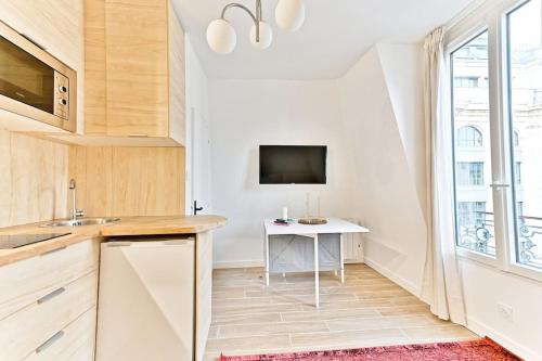 Il comprend une cuisine avec une table et une télévision murale. dans l'établissement Studio à 10 minutes de la Basilique du Sacré-Cœur, à Paris