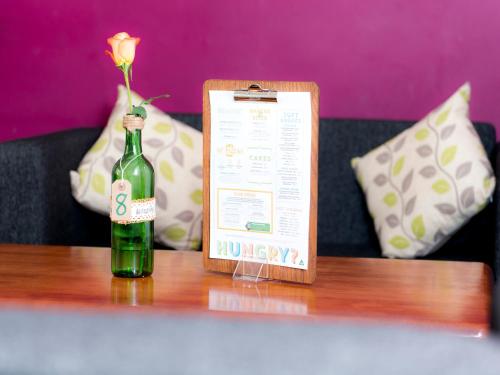 a bottle of wine on a table with a flower in it at YHA London Earl's Court in London
